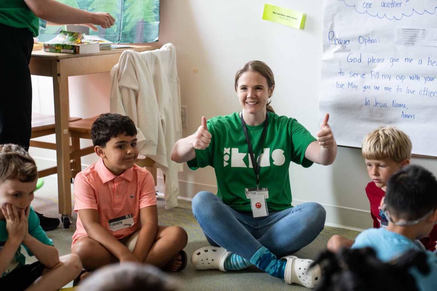 A VoxKids volunteer sitting on the floor with a small group of children during a teaching time.